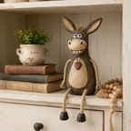 A rustic figurine of a donkey on a plank with rope legs hanging down