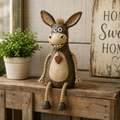A rustic figurine of a donkey on a plank with rope legs hanging down