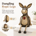 A rustic figurine of a donkey on a plank with rope legs hanging down
